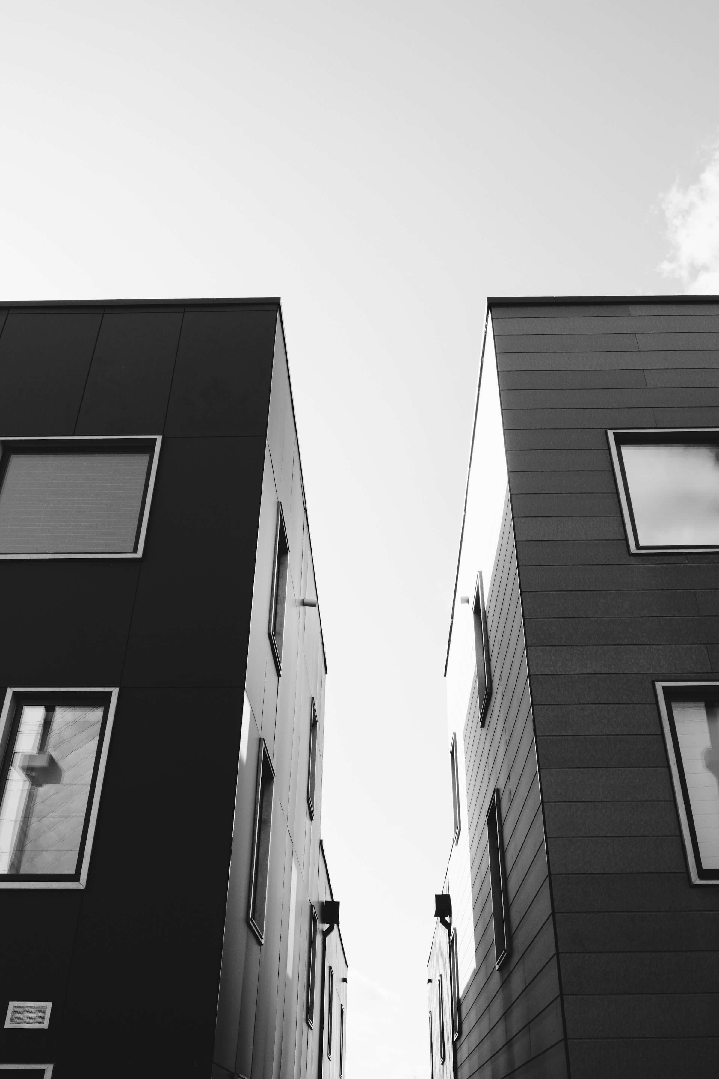 Two modern buildings viewed from below against the sky